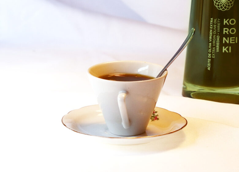 Taza de café acompañada de aceite de oliva virgen extra Isbilya, representando una experiencia sensorial única.